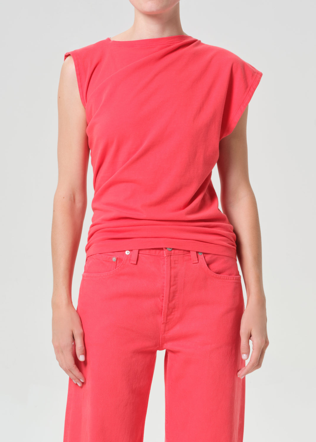 Person wearing a red sleeveless top and pants on a light gray background