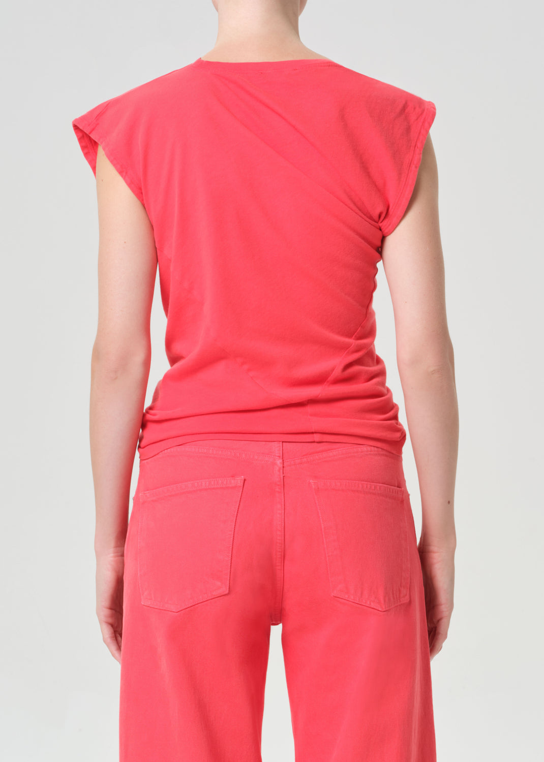 Person wearing a red sleeveless top and pants on a plain background