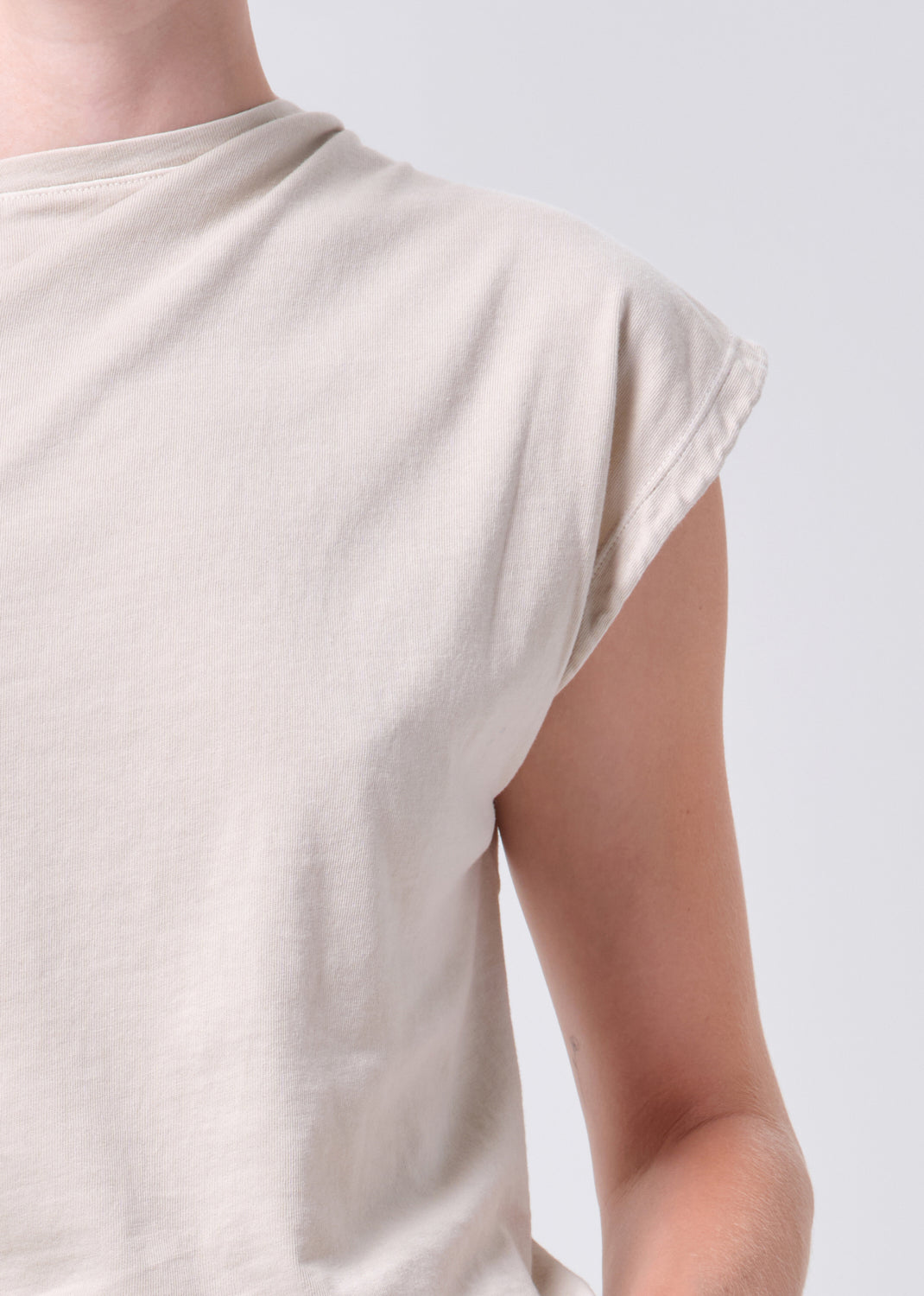 Beige sleeveless top worn by a person on a plain background