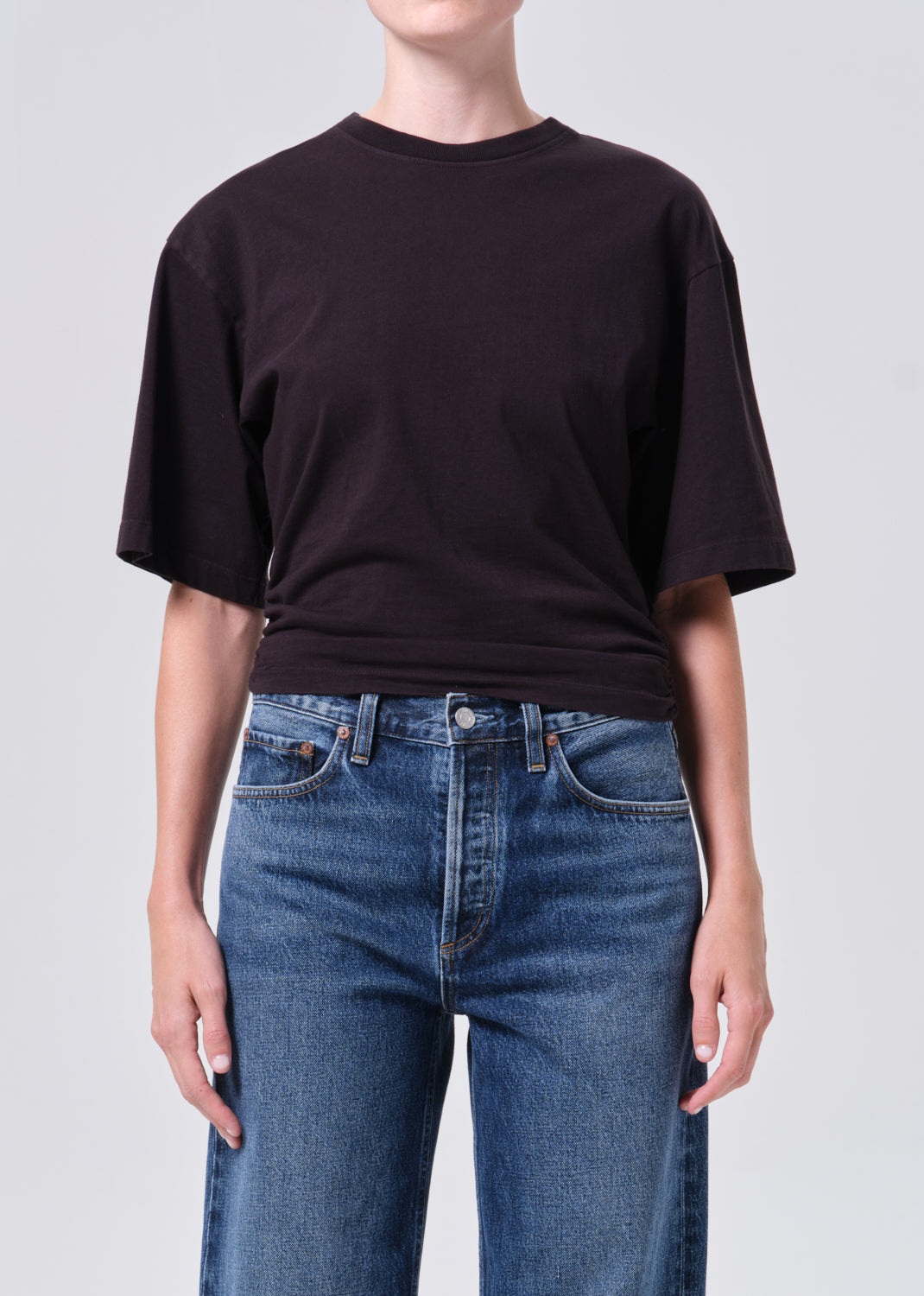 Person wearing a black t-shirt and blue jeans on a plain background