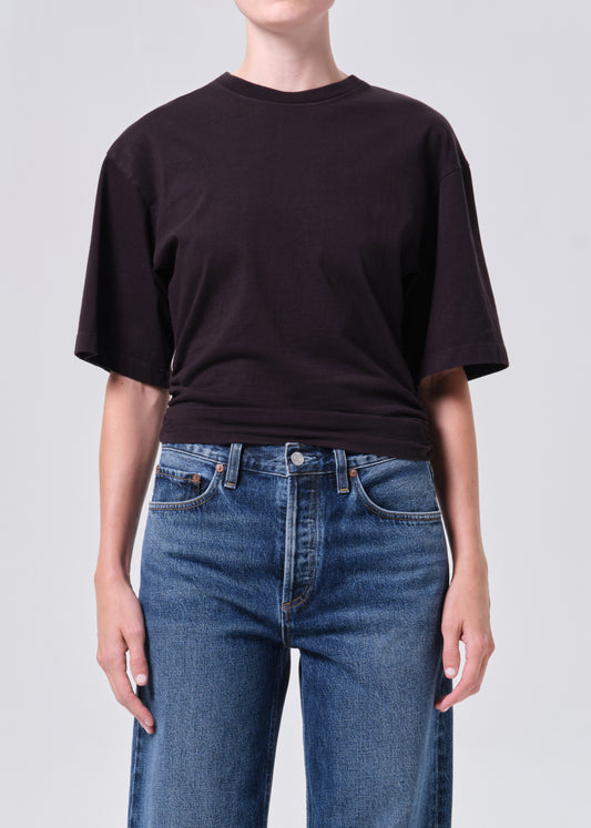 Person wearing a black t-shirt and blue jeans on a plain background