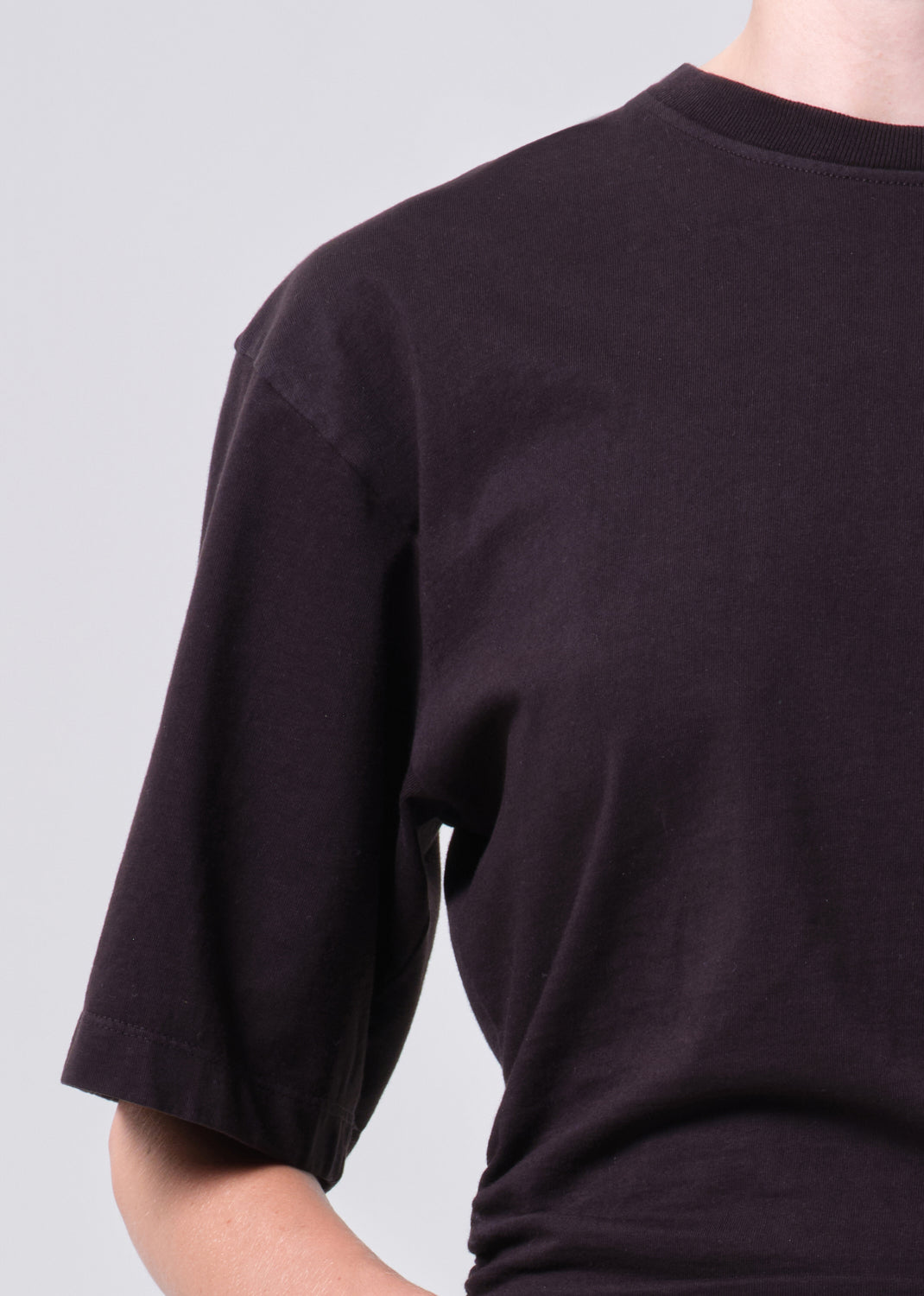 Black t-shirt worn by a person on a light gray background