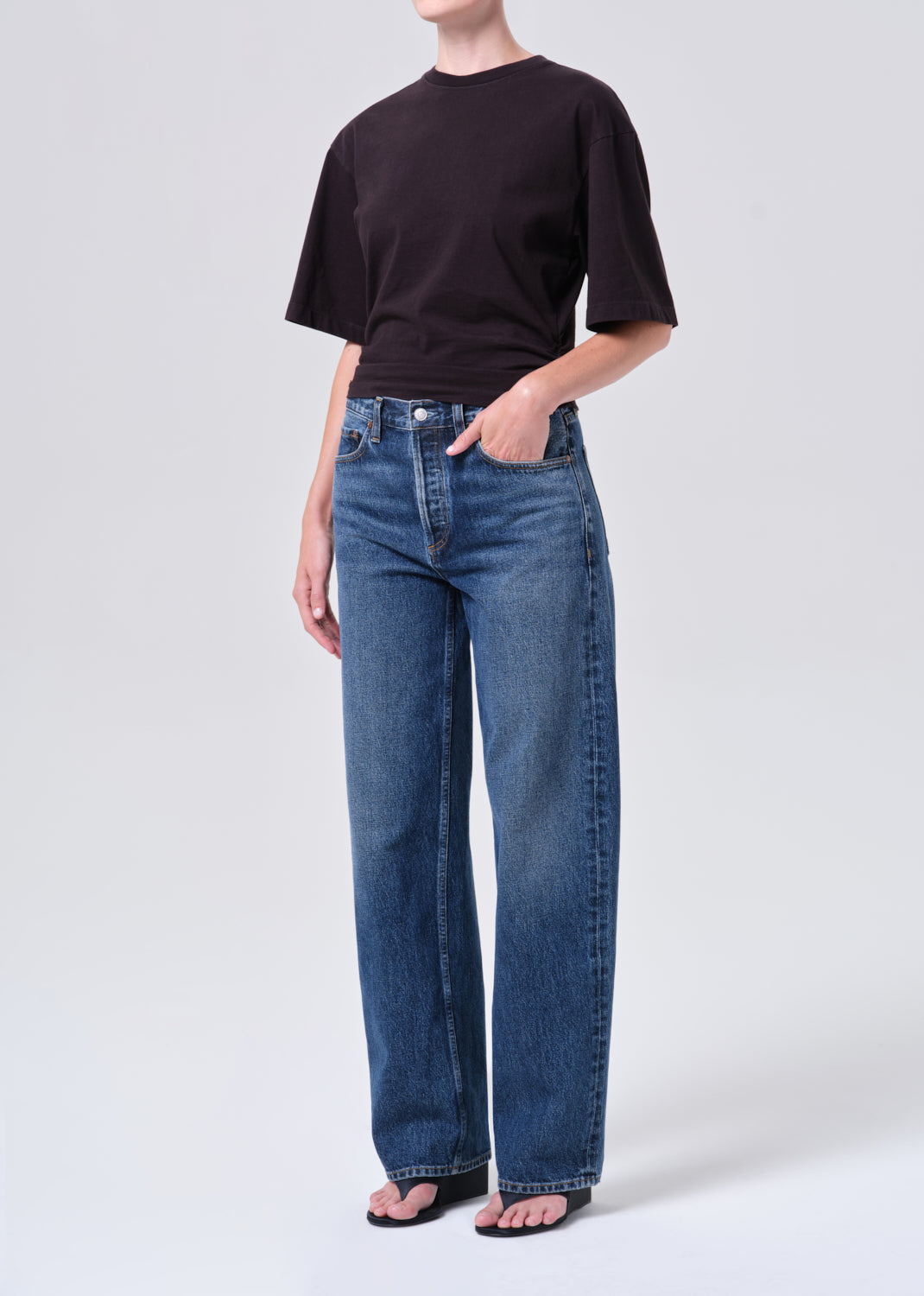 Person wearing a black t-shirt and blue jeans on a white background