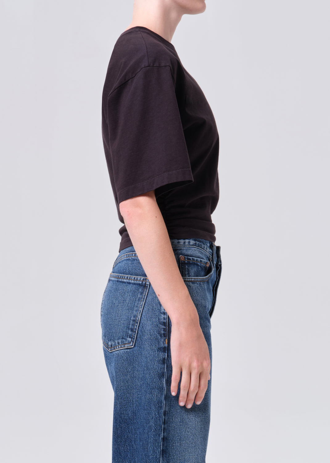 Person wearing a black t-shirt and blue jeans on a light gray background