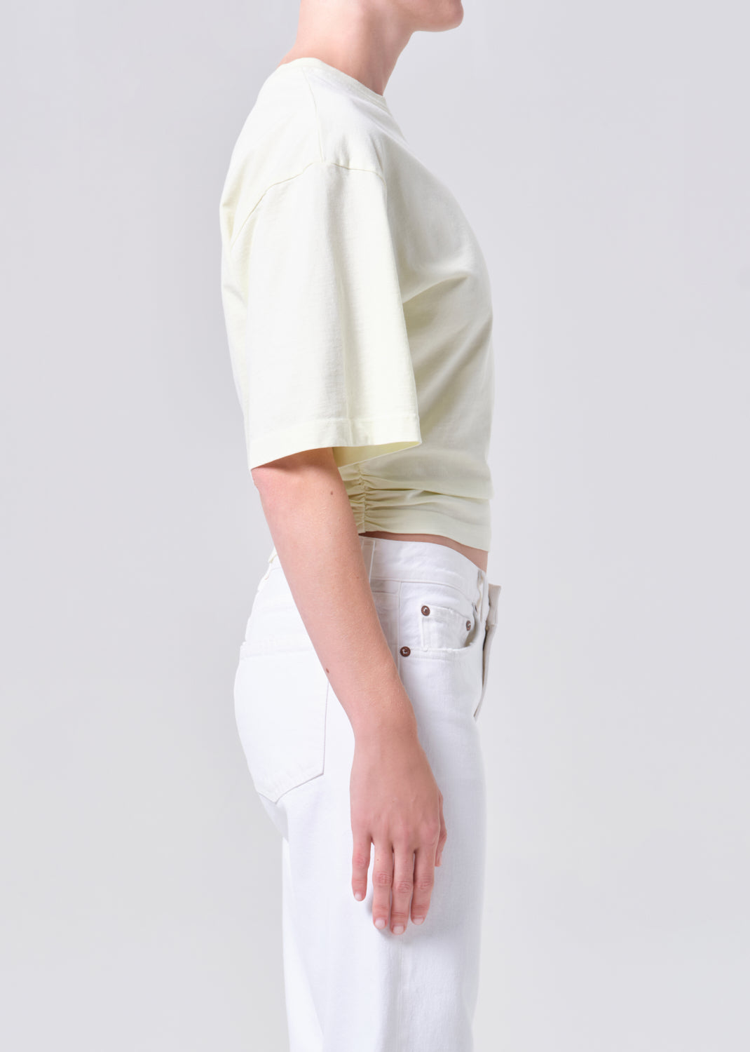 Person wearing a light-colored crop top and white pants on a plain background