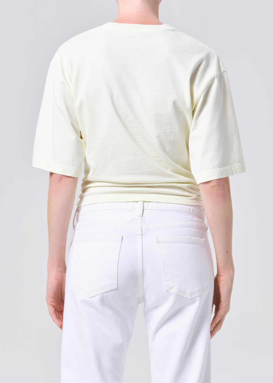 Person wearing a light-colored top and white pants on a plain background
