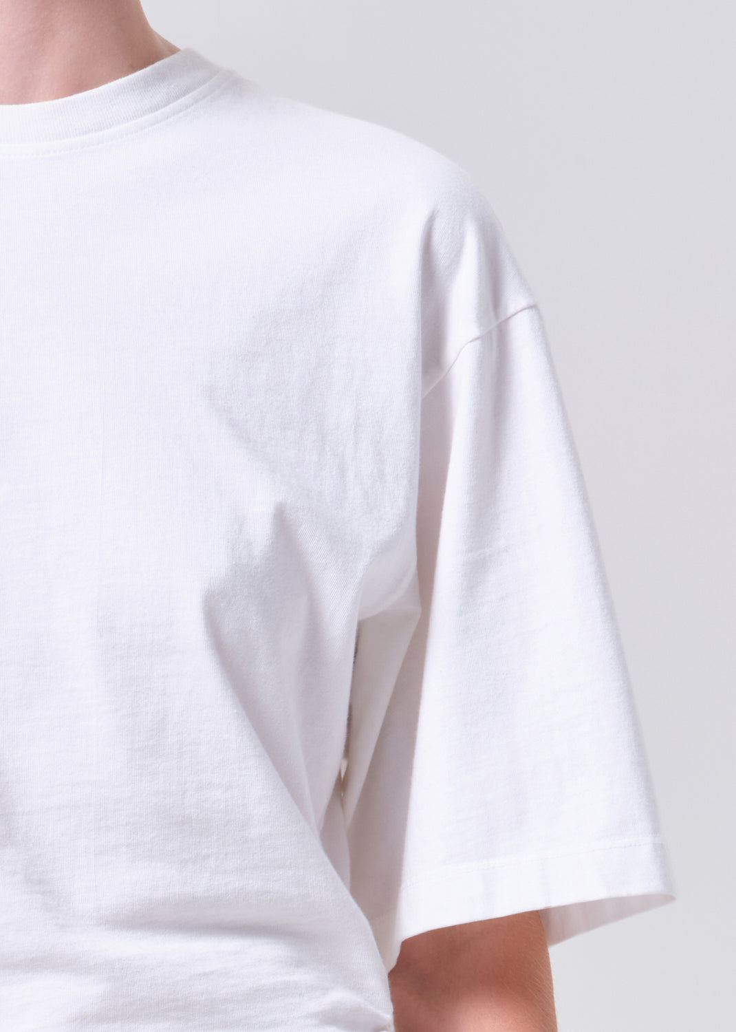 White t-shirt worn by a person on a plain background