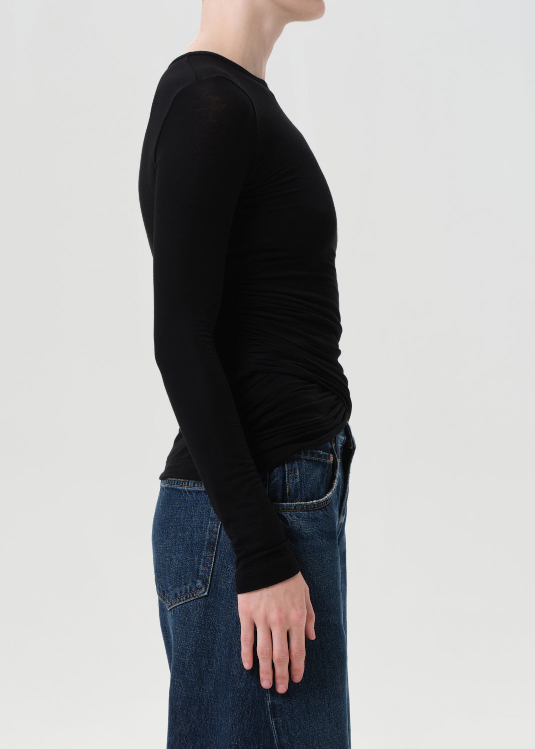 Person wearing a black long-sleeve shirt and blue jeans on a light gray background