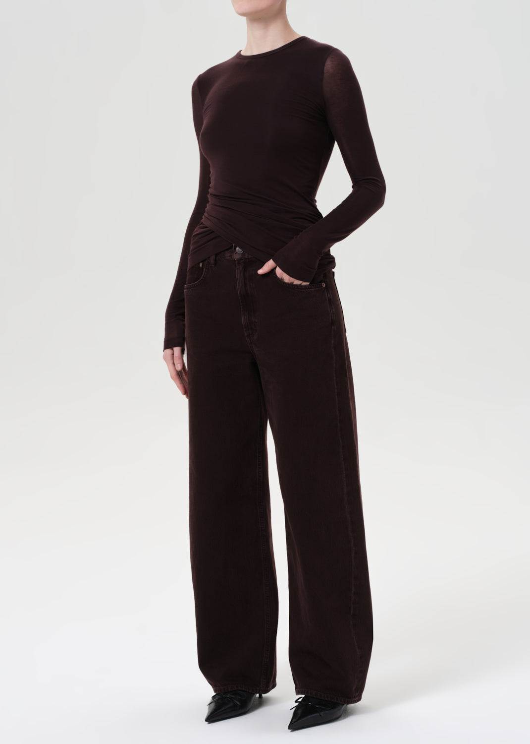 Person wearing a brown long-sleeve top and wide-leg pants on a white background