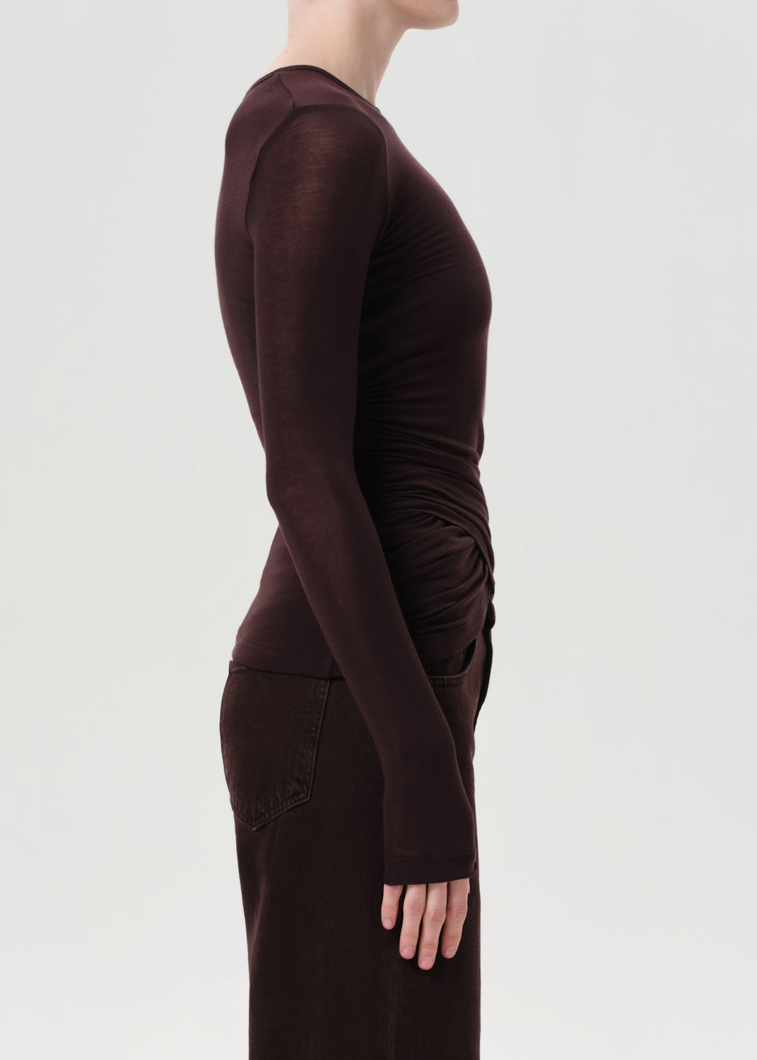 Brown long-sleeve top worn by a person on a light gray background