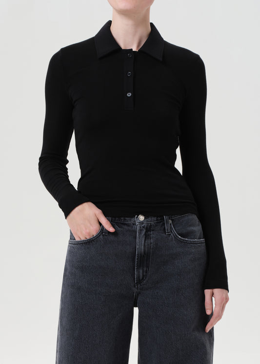 Person wearing a black long-sleeve polo shirt and dark jeans on a light gray background