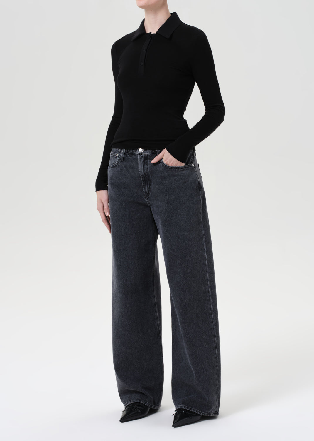 Person wearing a black sweater and gray jeans on a white background