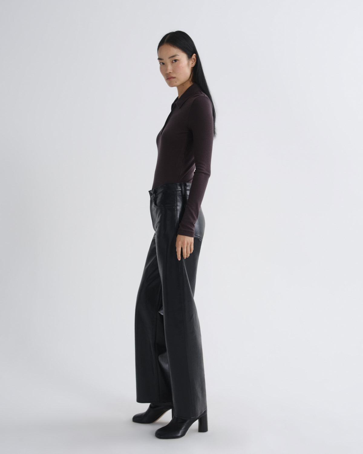 Person wearing a dark outfit with a high-waisted black leather skirt on a white background