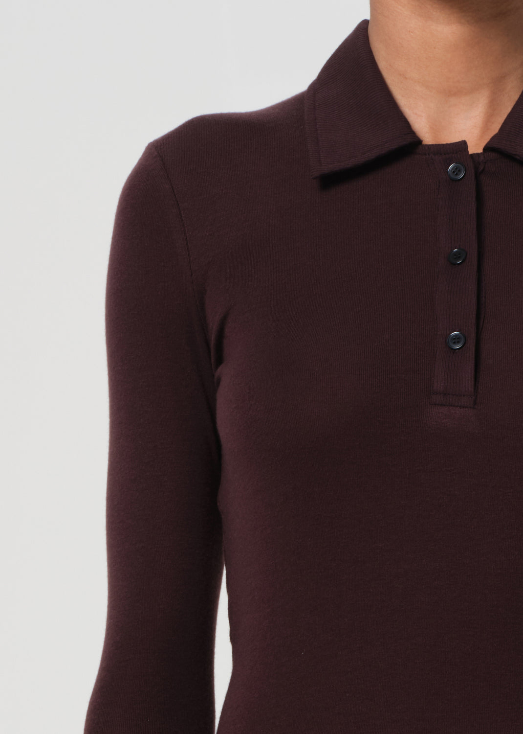 Close-up of a dark brown long-sleeve polo shirt with buttons on a light gray background