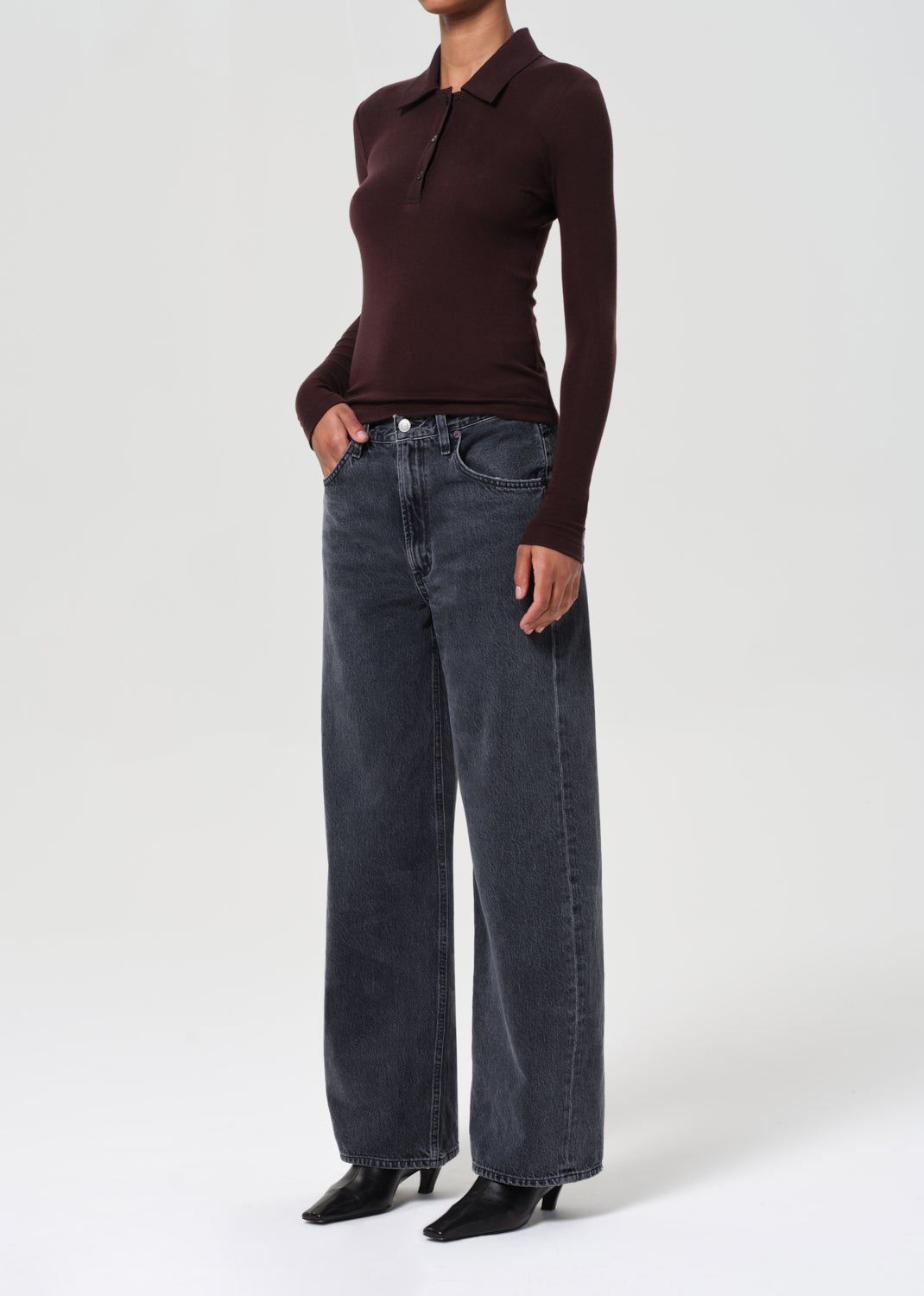 Person wearing a brown long-sleeve shirt and blue jeans on a white background