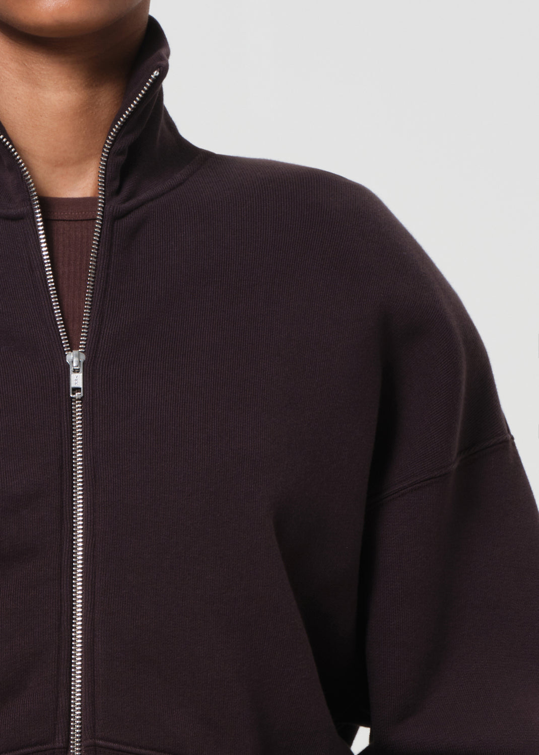 Close-up of a dark brown zip-up hoodie on a neutral background