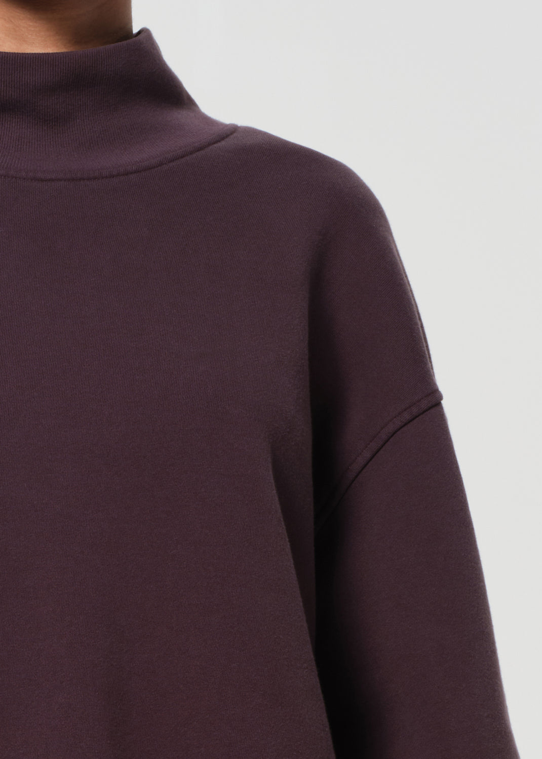 Close-up of a dark purple sweatshirt on a light gray background