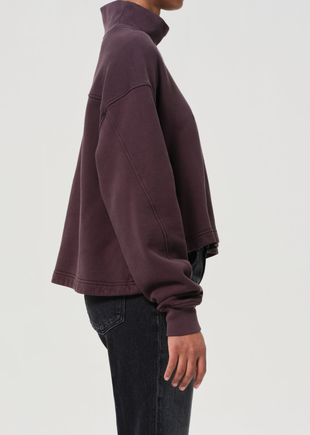 Person wearing a dark purple sweatshirt on a light gray background