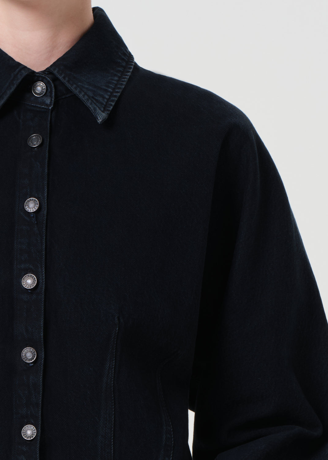 Close-up of a black button-up shirt with a plain background