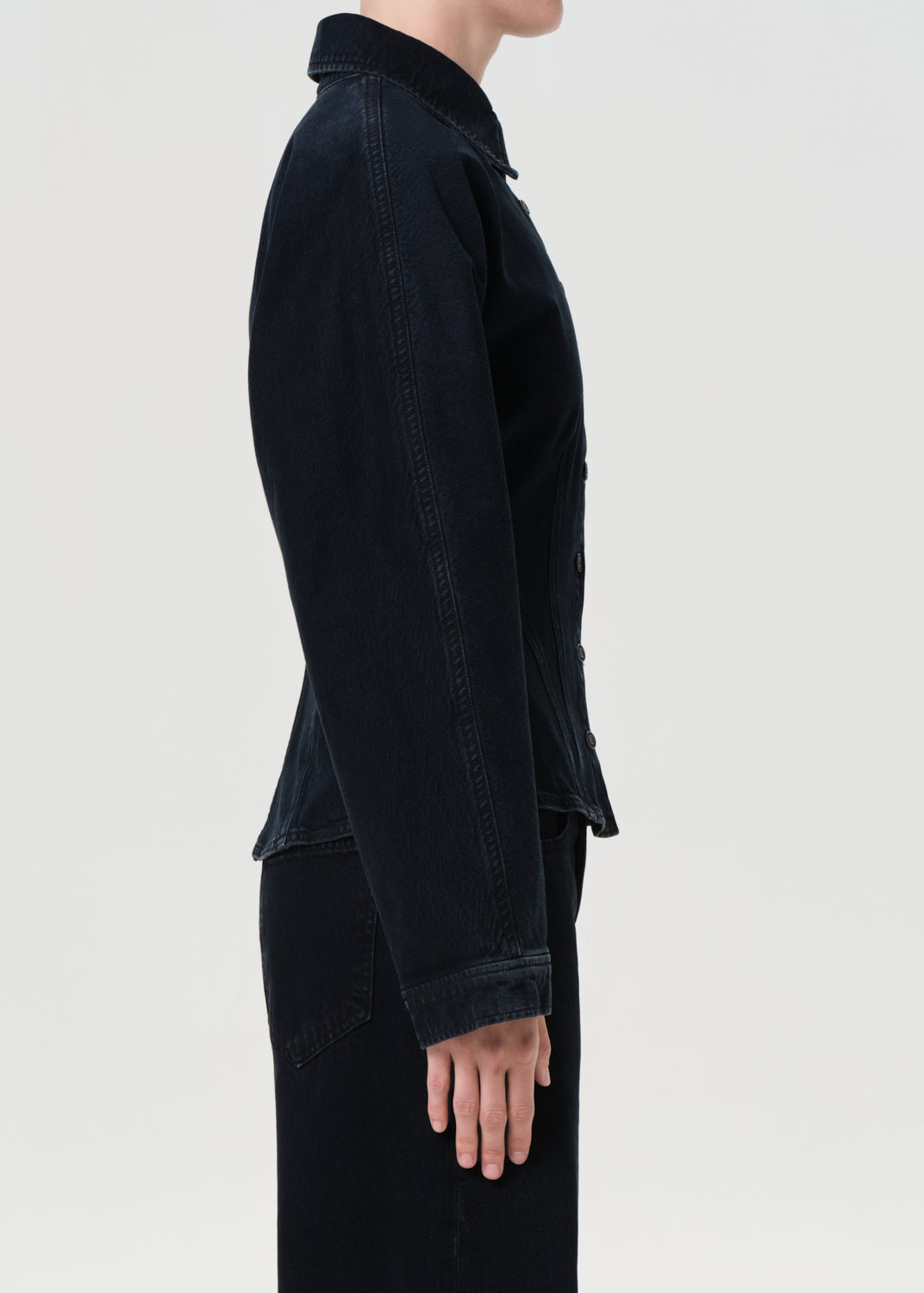 Person wearing a black jacket on a light gray background