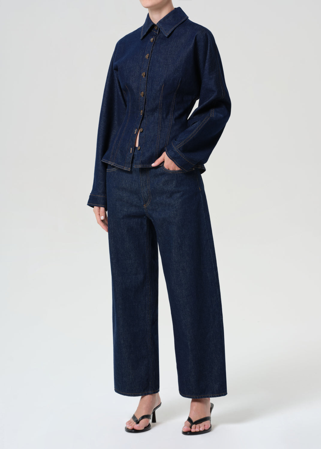 Person wearing a dark blue denim outfit on a white background