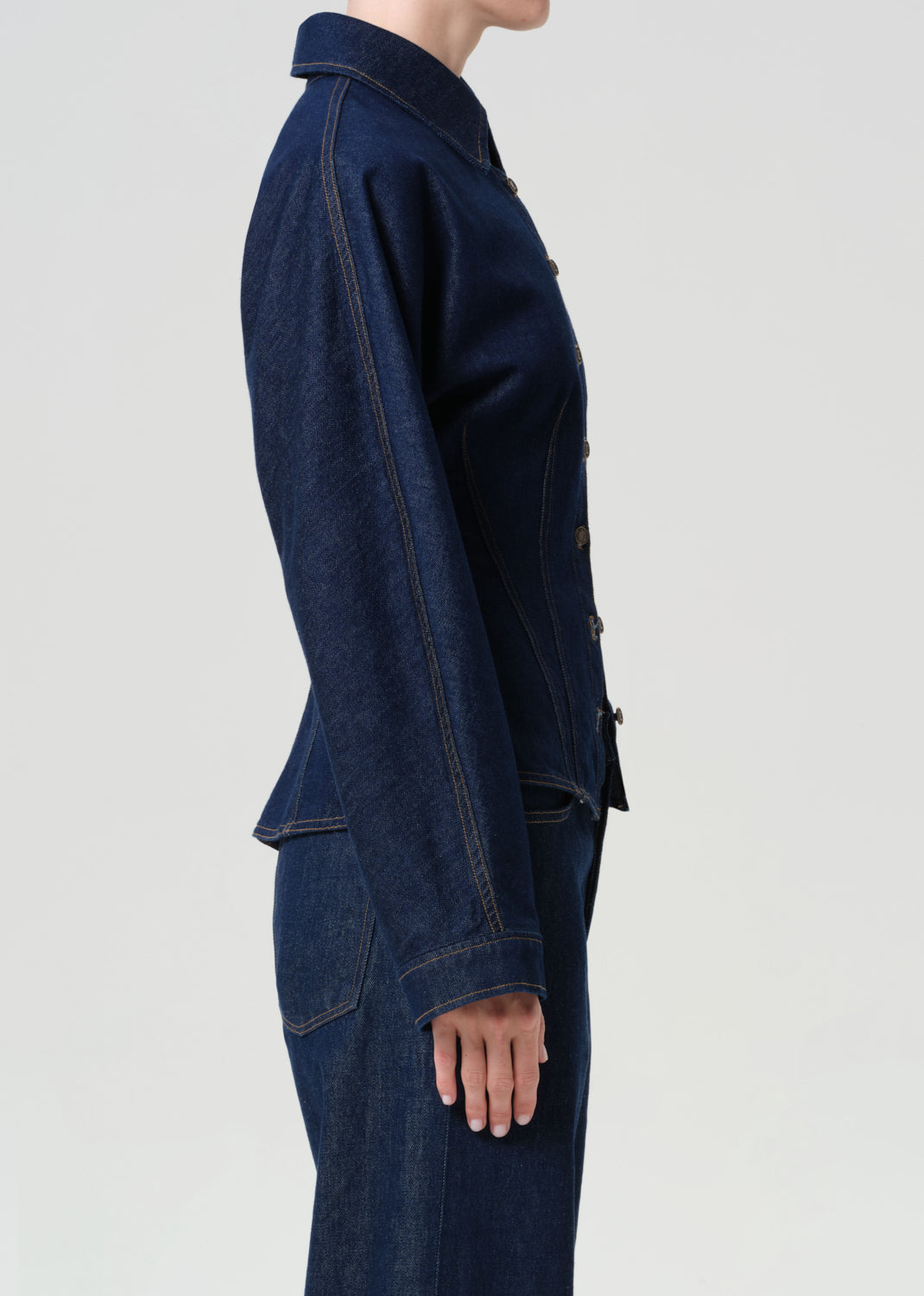 Dark blue denim jacket worn by a person on a light gray background