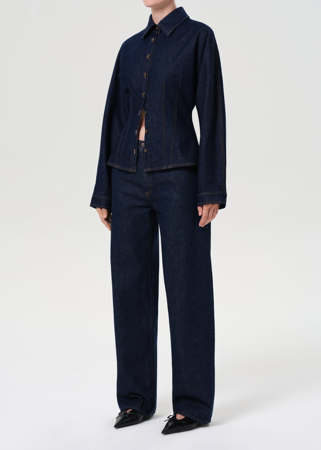 Person wearing a dark denim outfit on a white background