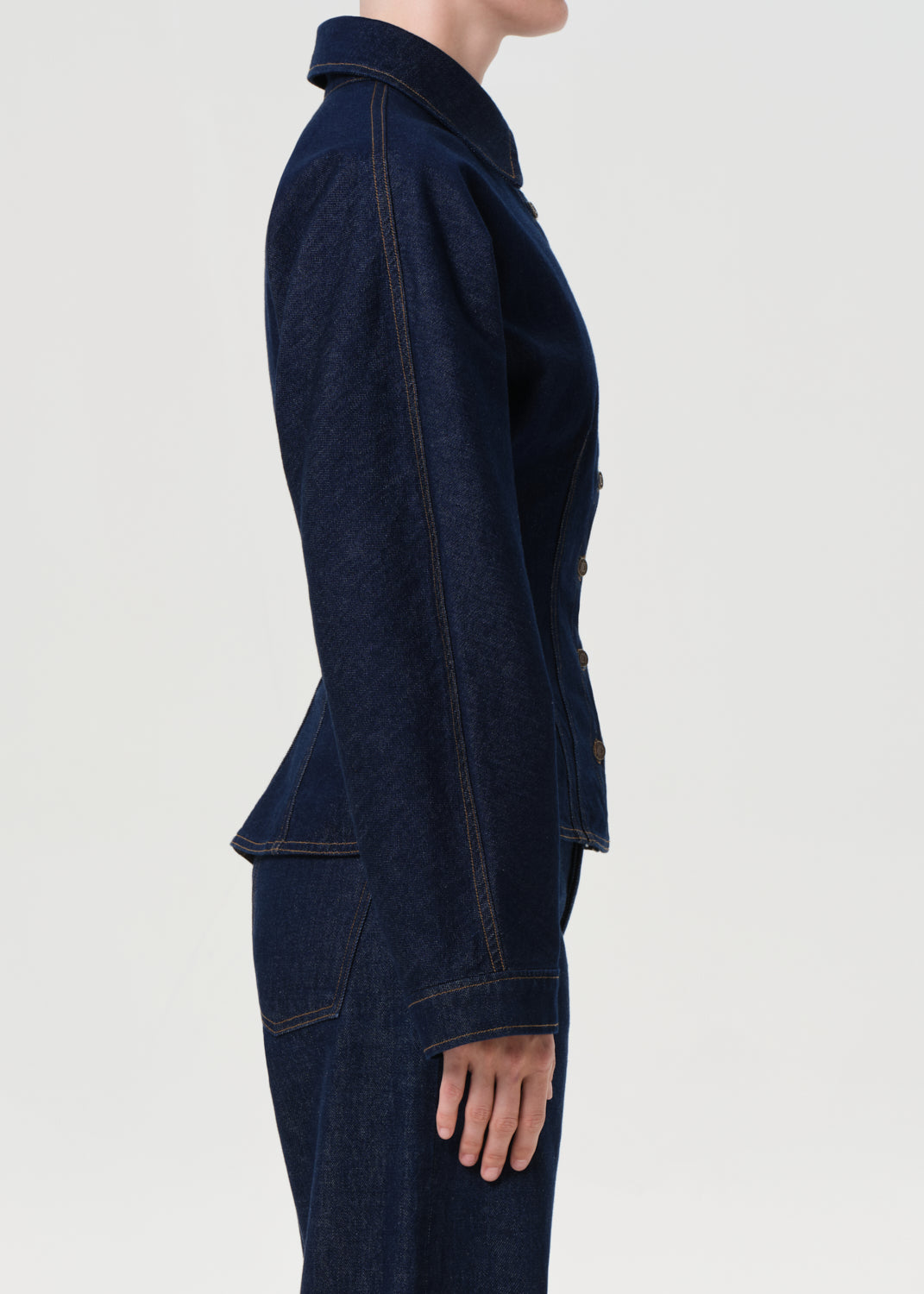 Person wearing a dark blue denim jacket on a light gray background