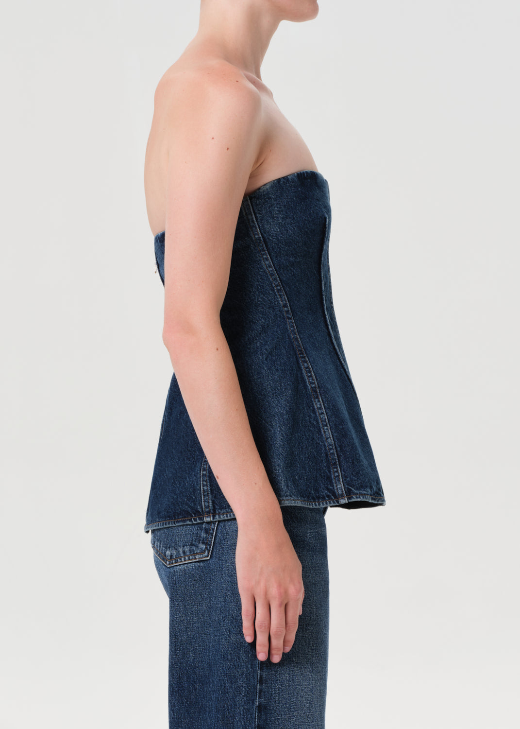 Person wearing a strapless denim top and jeans on a plain background