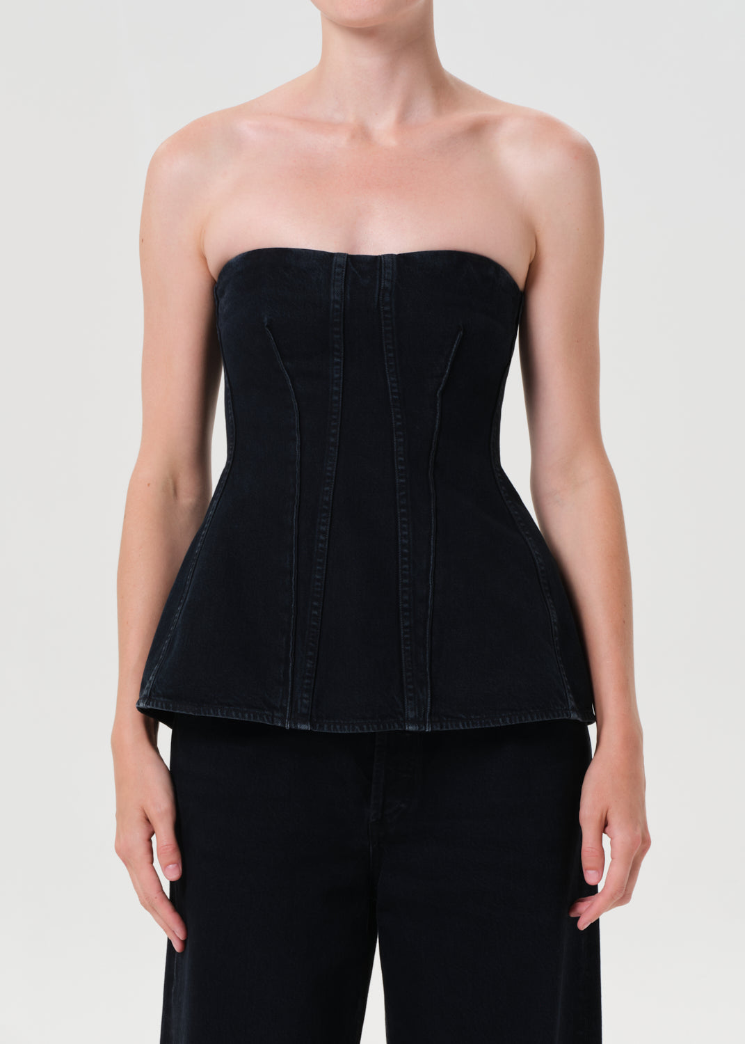 Black strapless top worn by a model on a plain background