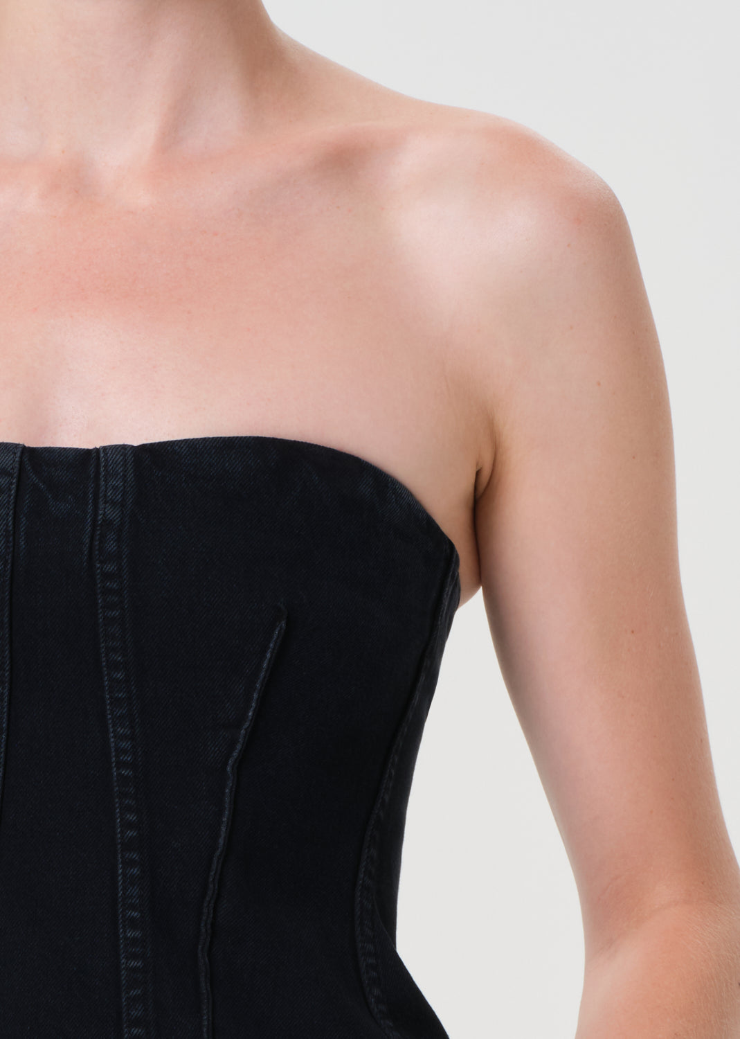 Black strapless top worn by a person on a plain background