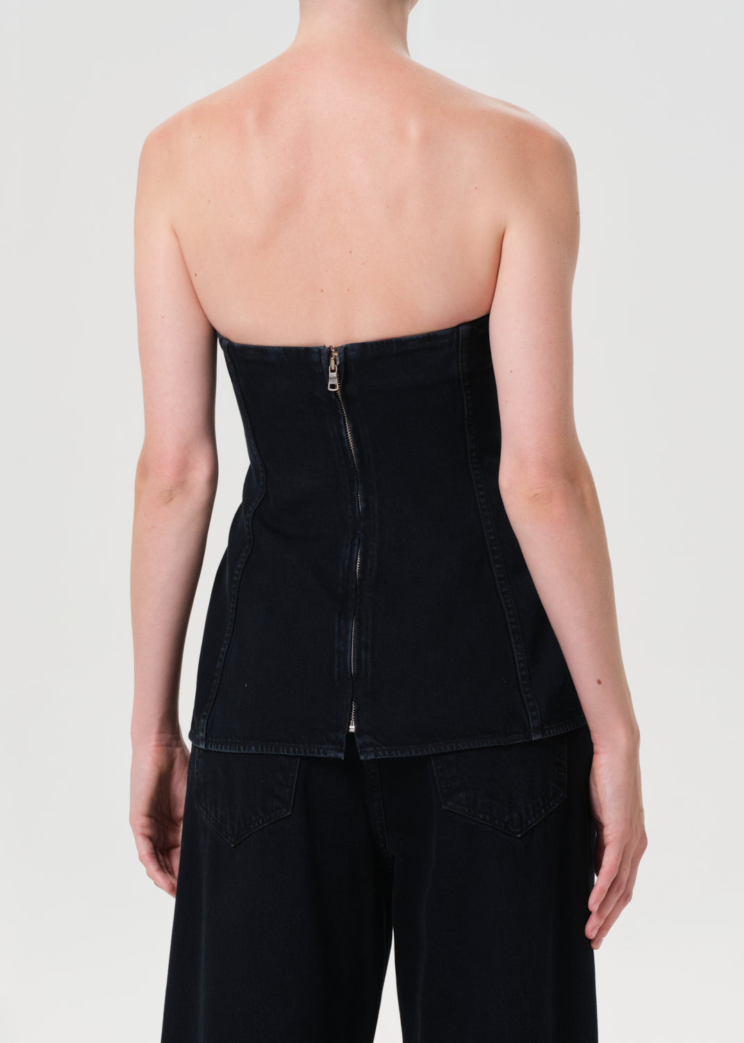 Black strapless top with zipper on a plain background