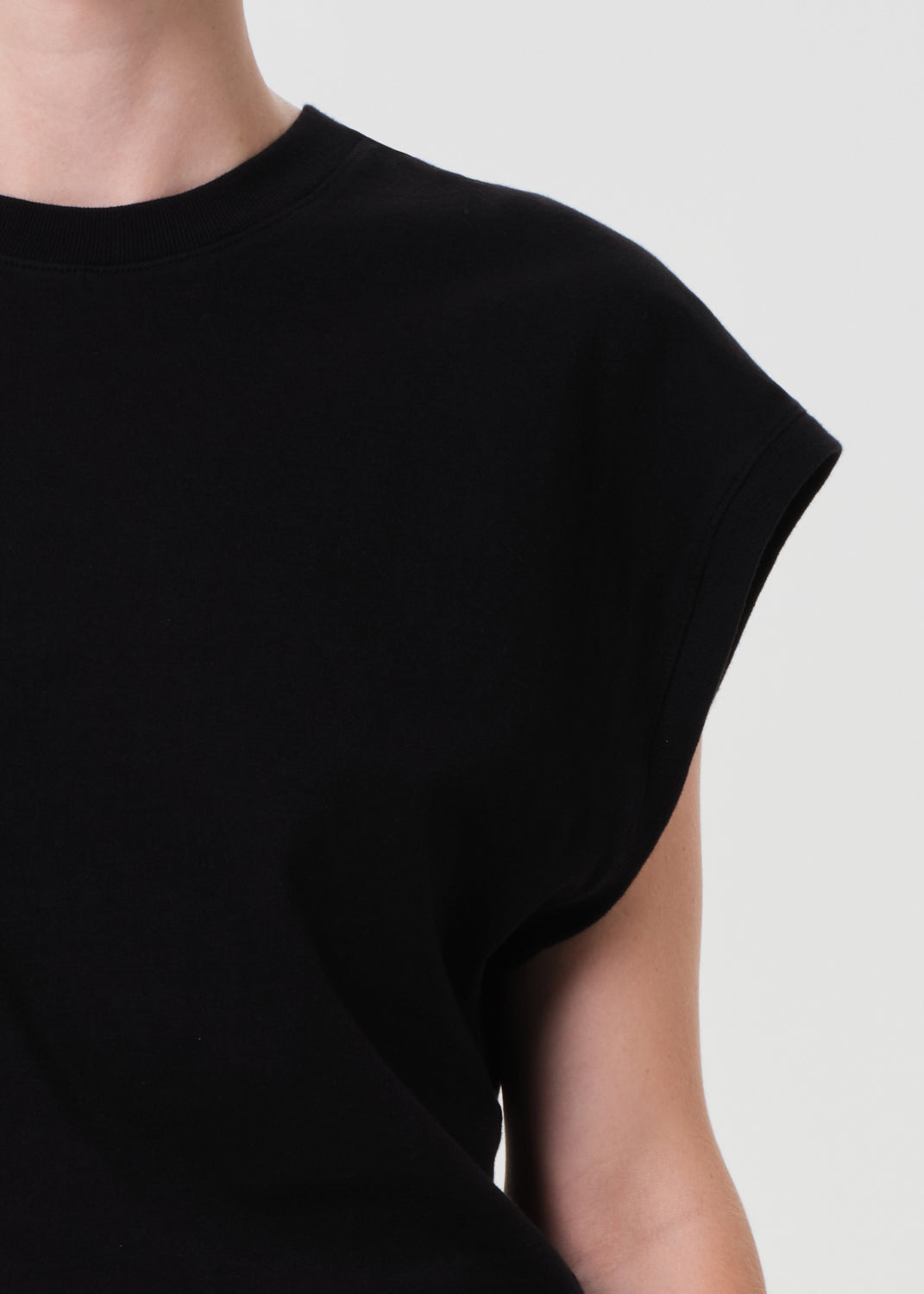 Black sleeveless top worn by a person on a plain background