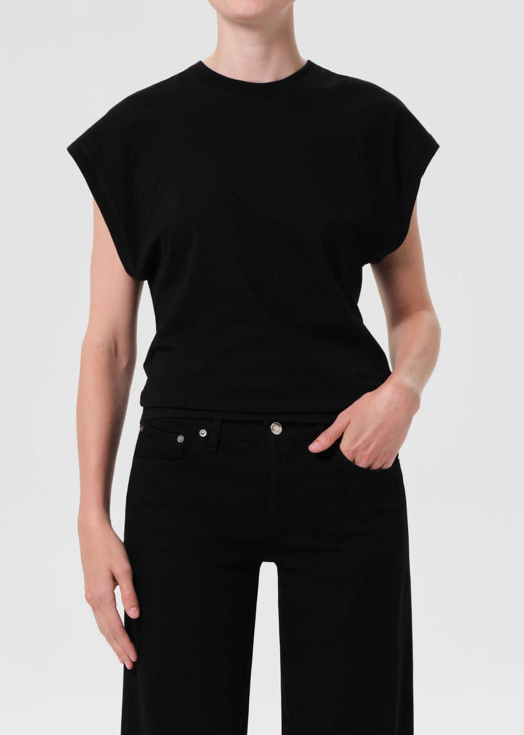 Person wearing a black sleeveless top and black pants on a white background