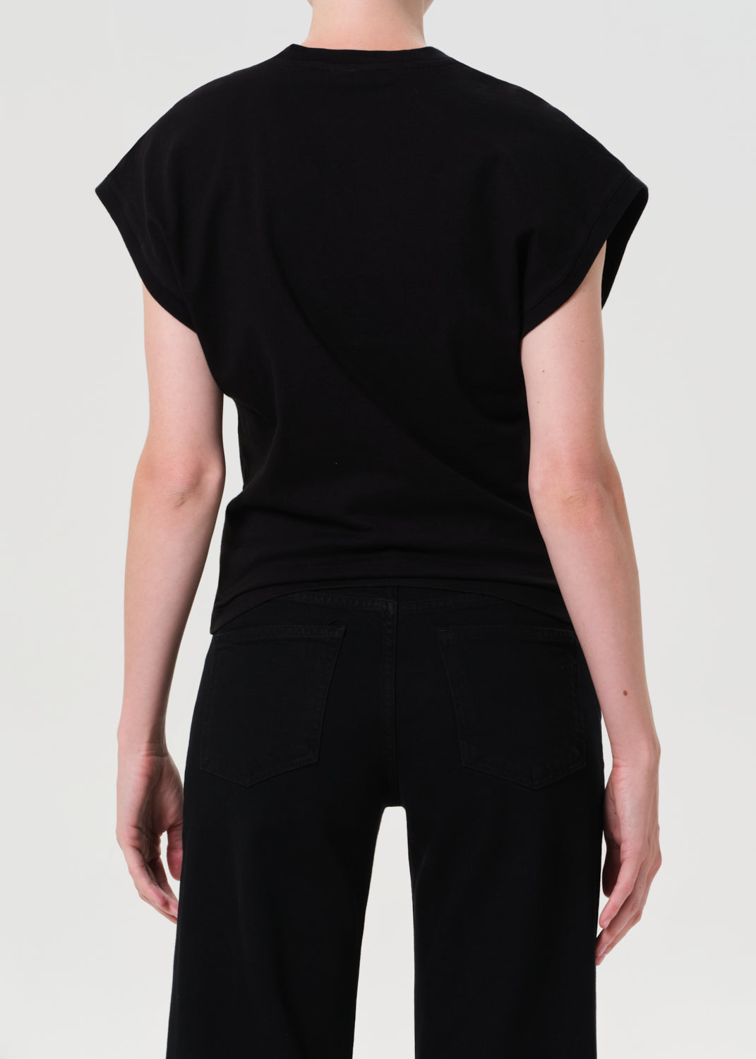 Person wearing a black sleeveless top and pants on a white background
