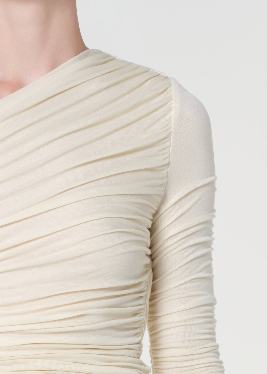 Close-up of a cream-colored long-sleeve dress with ruched detailing on a white background