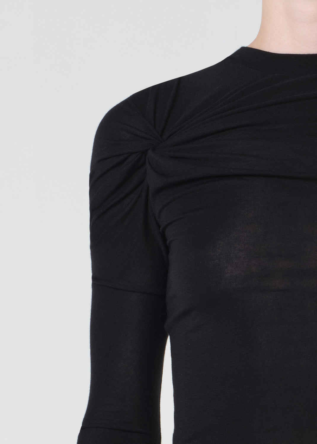 Black long-sleeve top with a knot detail on a light gray background