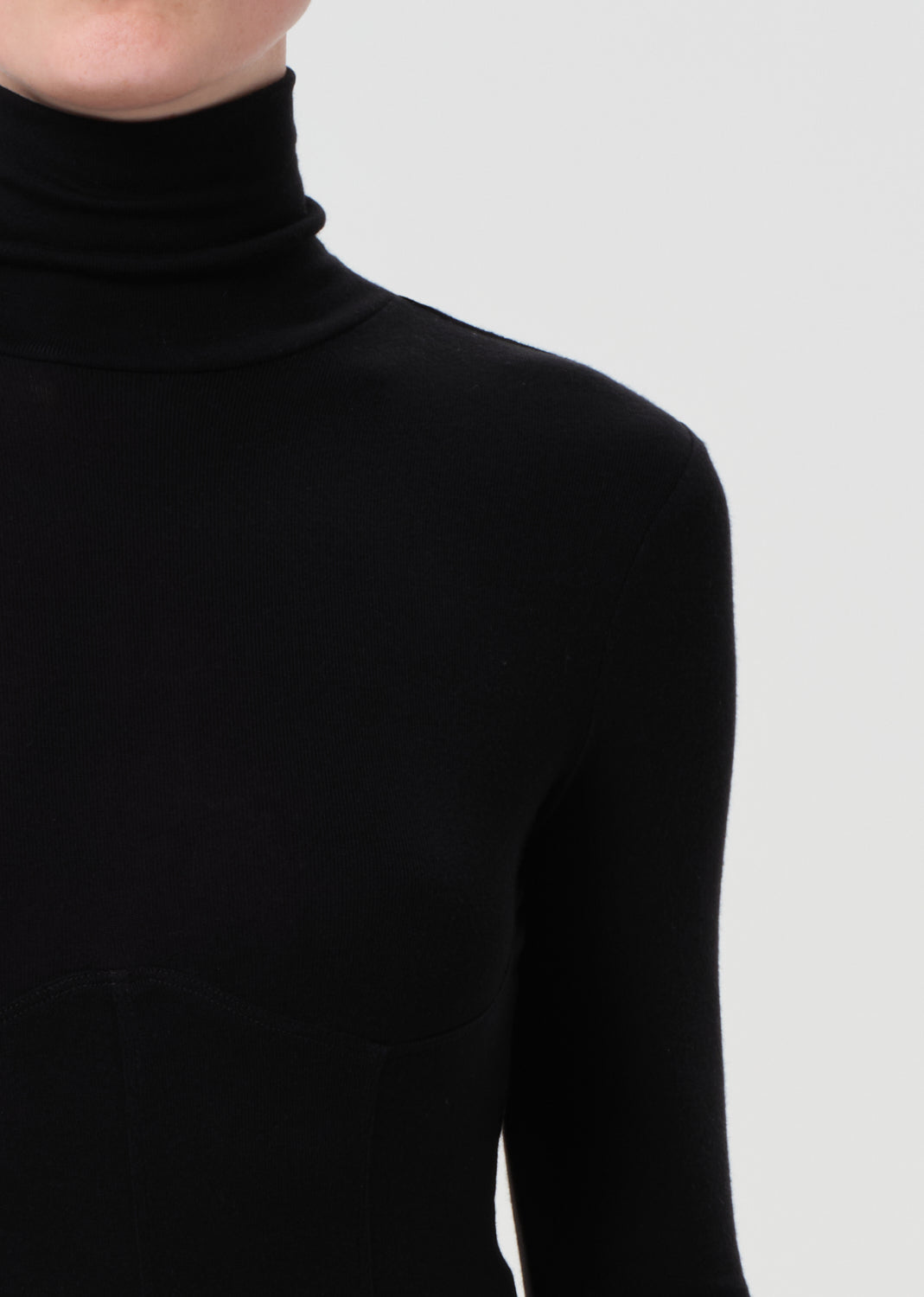 Black turtleneck sweater worn by a person on a light gray background