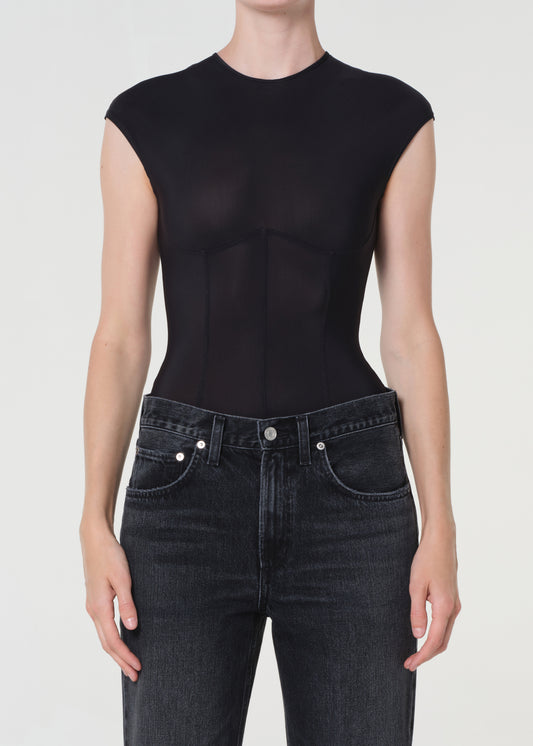 Person wearing a black sleeveless top and dark jeans on a white background