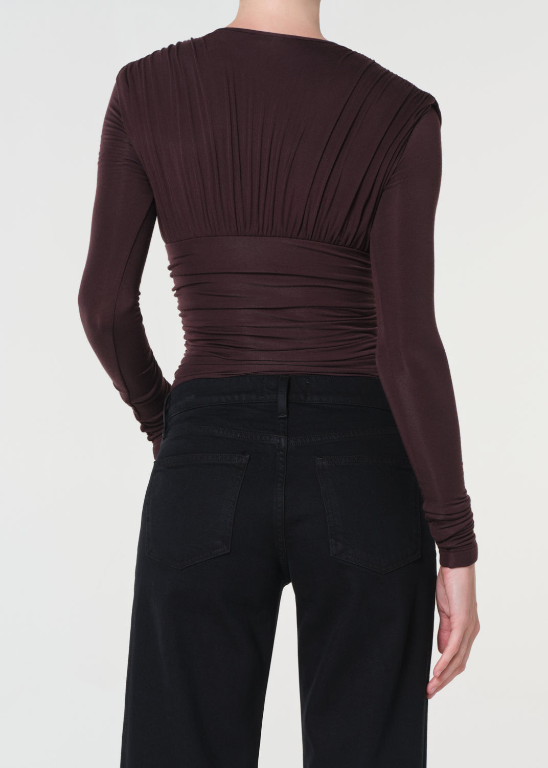 Brown long-sleeve top worn by a person on a white background