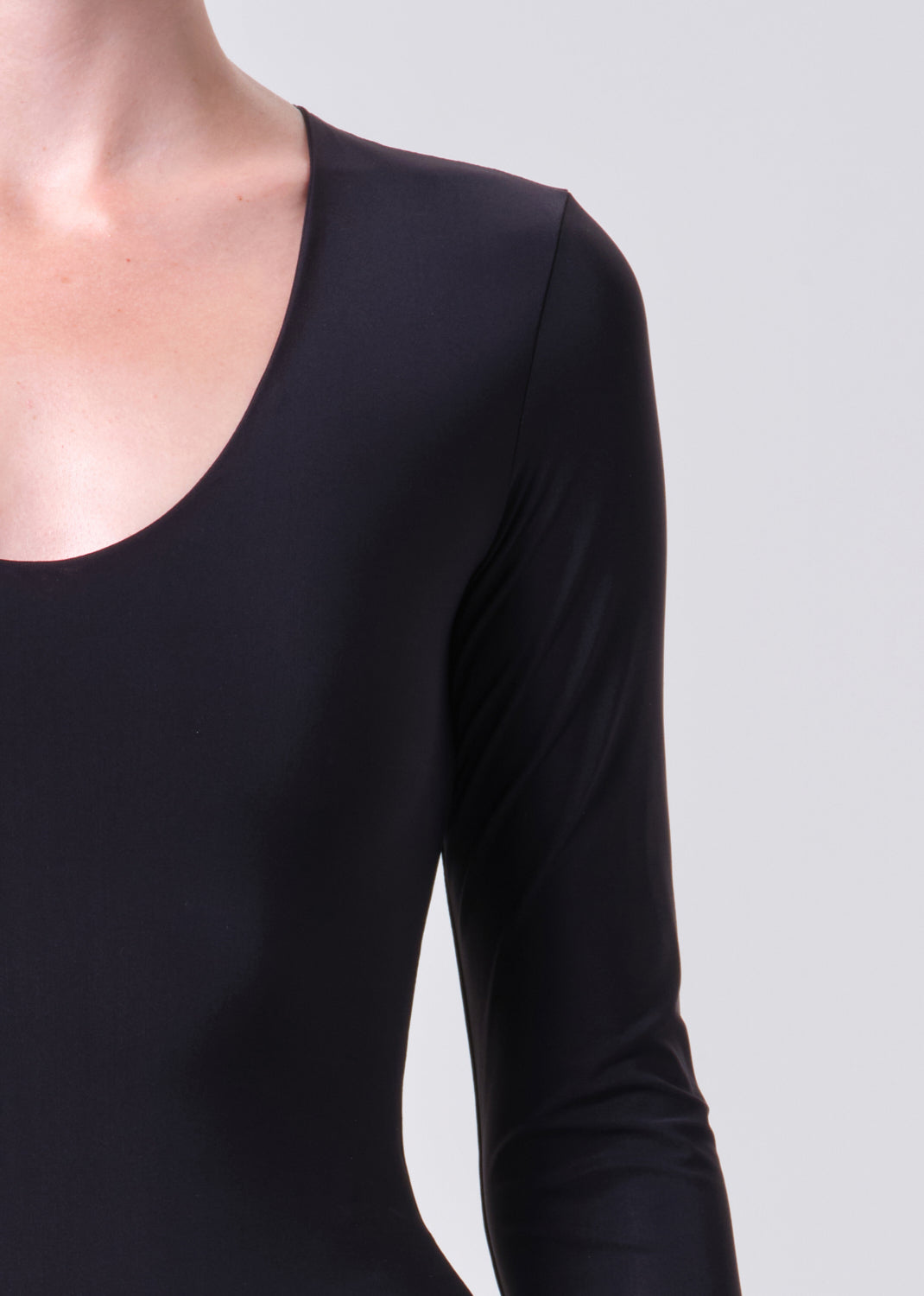 Black long-sleeve top worn by a person on a light gray background