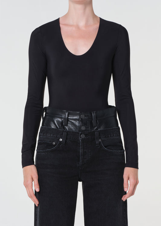 Person wearing a black long-sleeve top and black leather pants on a white background