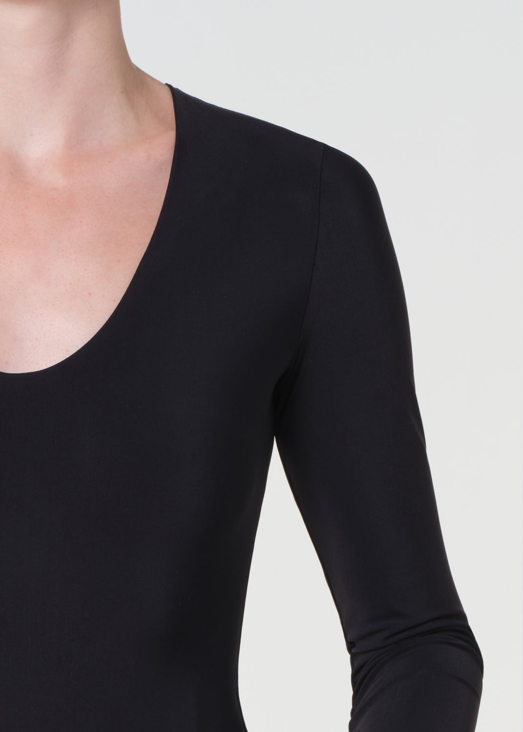 Black long-sleeve top worn by a person on a light gray background