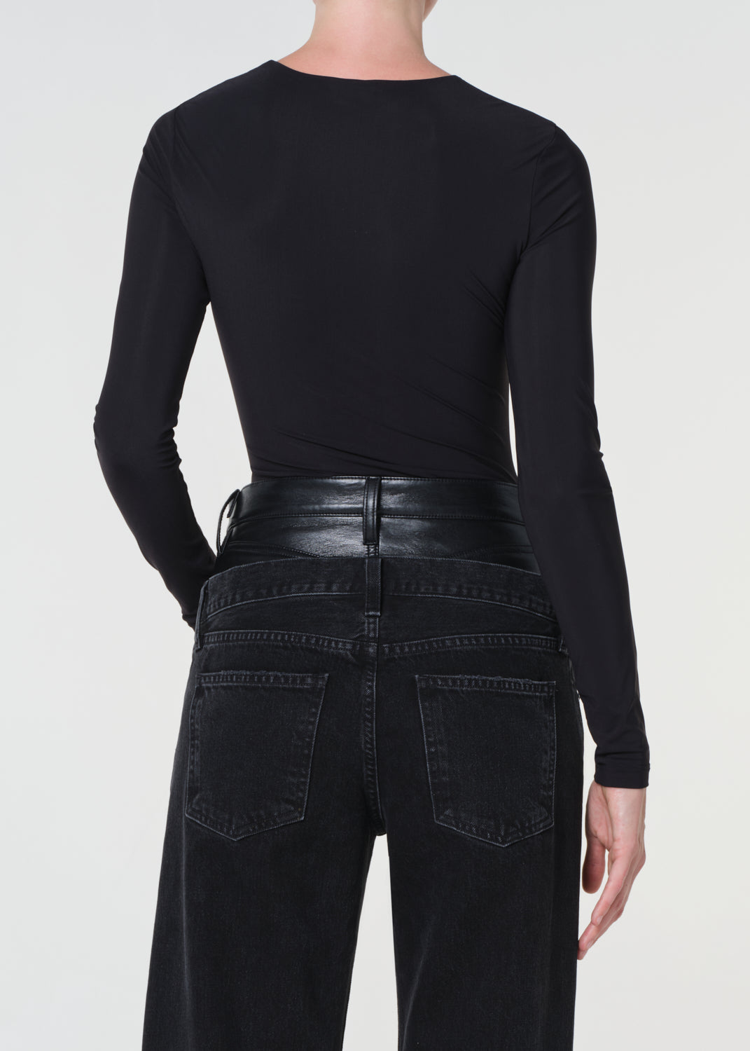 Person wearing a black long-sleeve top and black pants on a white background