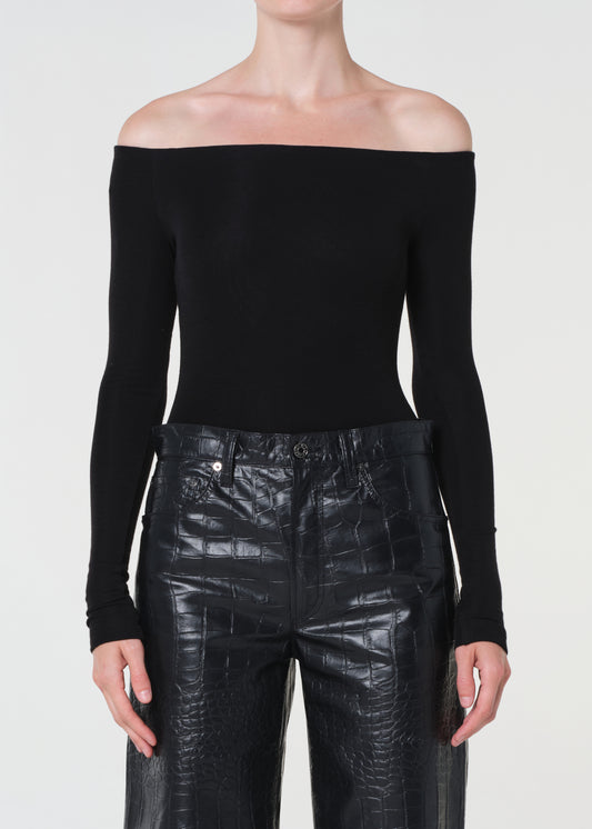 Person wearing a black off-shoulder top and black leather pants on a white background