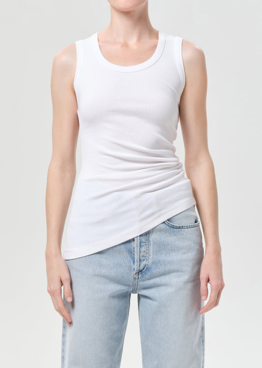 Person wearing a white tank top and light blue jeans on a plain background