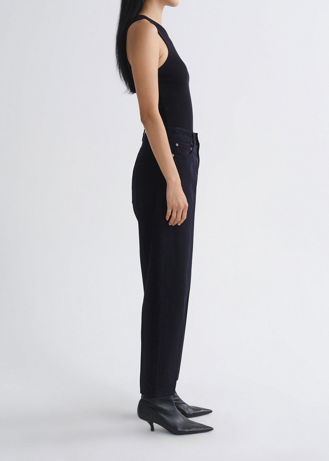 Person wearing a black sleeveless top and black pants on a grey background