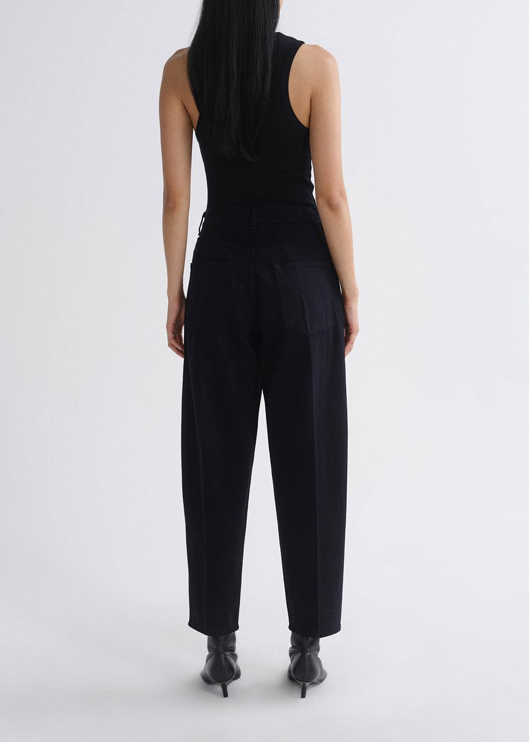 Person wearing a black sleeveless jumpsuit on a grey background