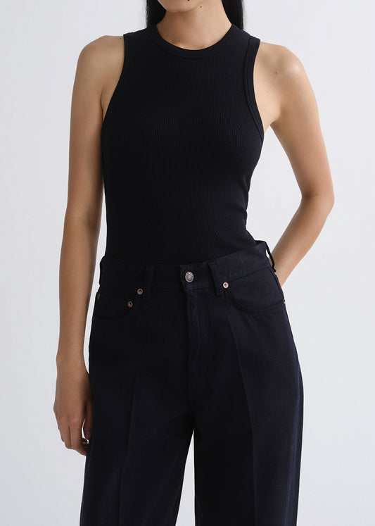 Person wearing a black sleeveless top and black pants on a grey background