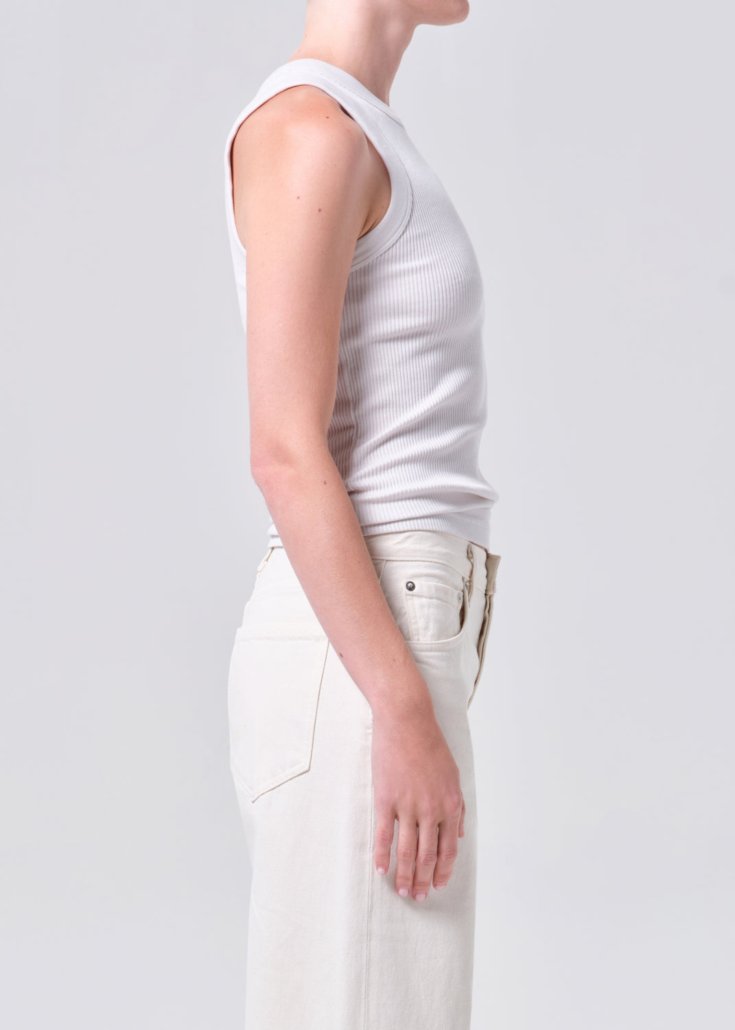 Person wearing a white sleeveless top and pants on a plain background